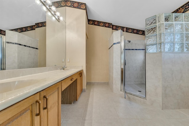 bathroom with double vanity, tile patterned flooring, a walk in shower, and a sink