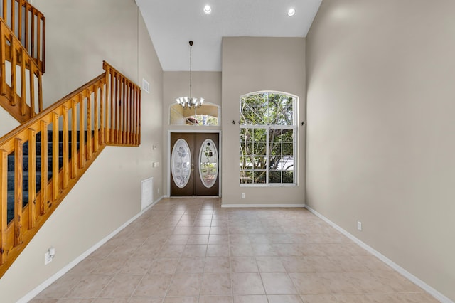 foyer entrance featuring a notable chandelier, visible vents, baseboards, stairs, and a towering ceiling