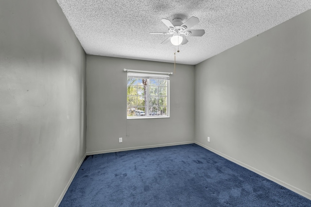 spare room with a textured ceiling, carpet floors, ceiling fan, and baseboards