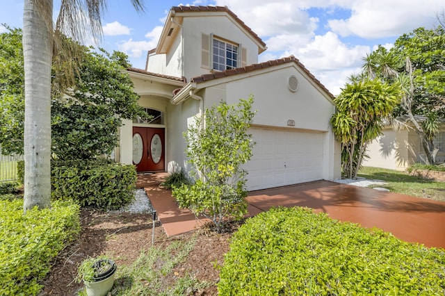 mediterranean / spanish house featuring a garage, driveway, a tiled roof, and stucco siding