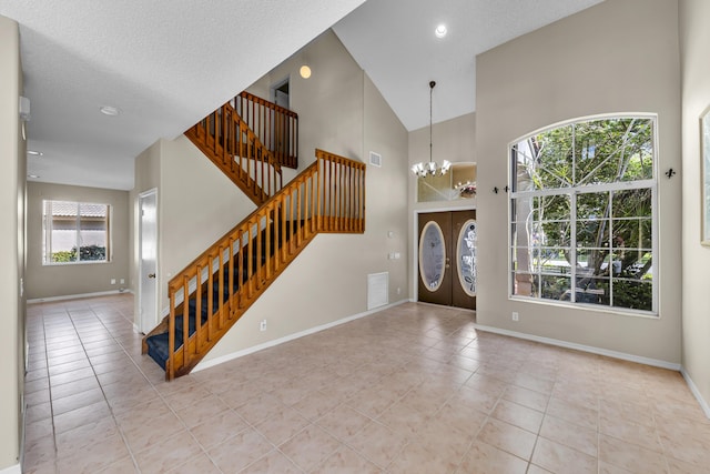 foyer with baseboards, stairway, an inviting chandelier, tile patterned flooring, and high vaulted ceiling