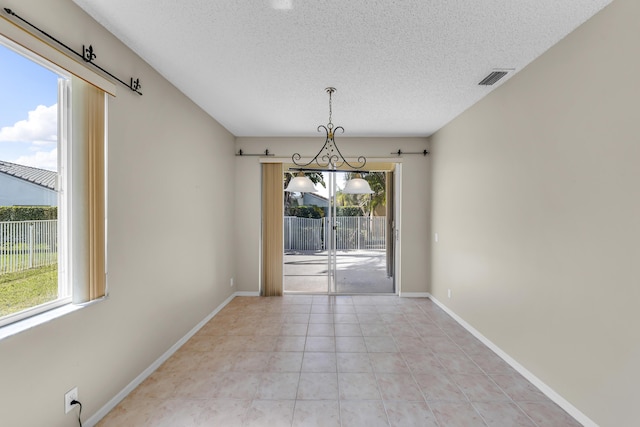 spare room with light tile patterned floors, baseboards, visible vents, and a textured ceiling