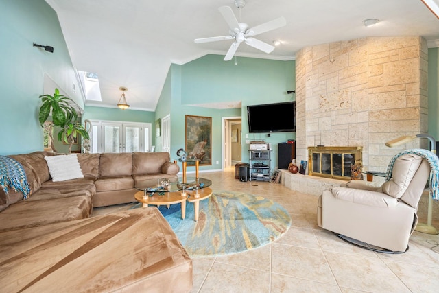 tiled living area featuring ceiling fan, french doors, a stone fireplace, and lofted ceiling with skylight