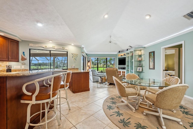 dining area featuring light tile patterned floors, vaulted ceiling, visible vents, and crown molding