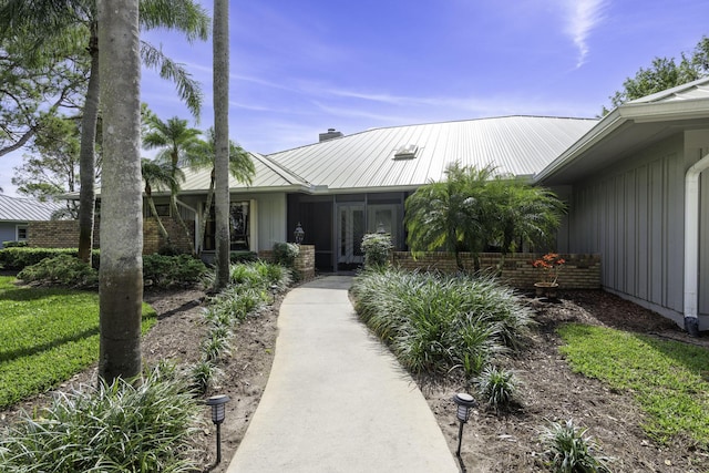 view of front facade featuring a standing seam roof, metal roof, brick siding, and a chimney