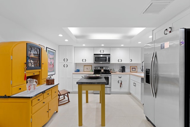 kitchen featuring a tray ceiling, stainless steel appliances, recessed lighting, visible vents, and decorative backsplash