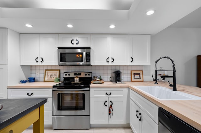 kitchen with tasteful backsplash, white cabinetry, stainless steel appliances, and a sink