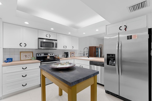 kitchen featuring appliances with stainless steel finishes, a sink, visible vents, and tasteful backsplash