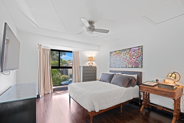 bedroom featuring attic access, dark wood-style flooring, and ceiling fan