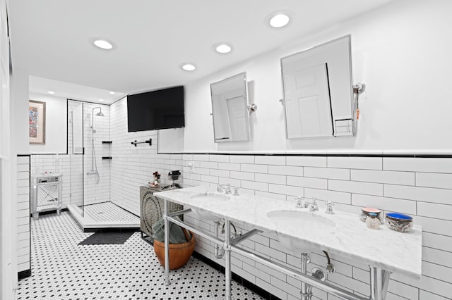 full bath with recessed lighting, a sink, tile walls, tiled shower, and wainscoting