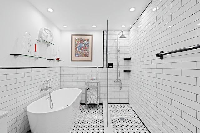 bathroom with tile walls, recessed lighting, a freestanding bath, wainscoting, and tiled shower