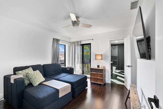 living room featuring a ceiling fan, visible vents, and dark wood-type flooring