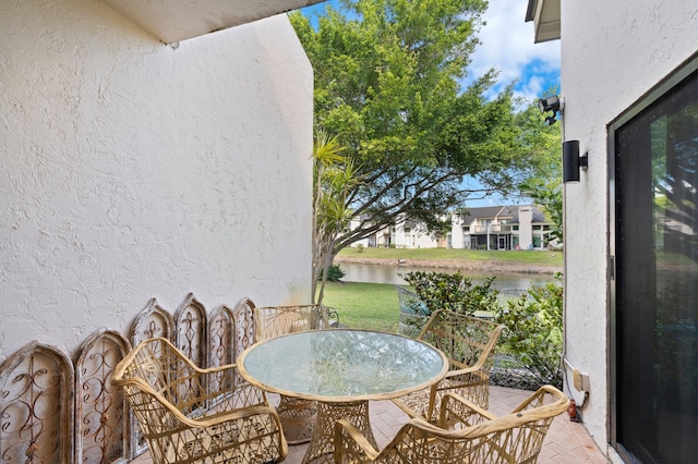 balcony with outdoor dining area and a water view