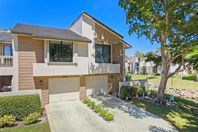 view of front of property with an attached garage, a shingled roof, decorative driveway, and stucco siding