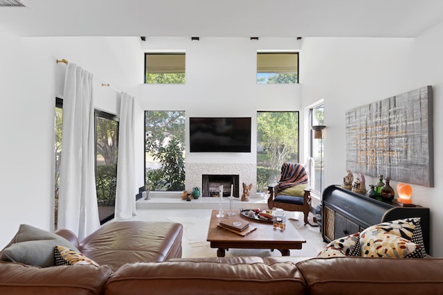 living room featuring a high ceiling and a fireplace with raised hearth