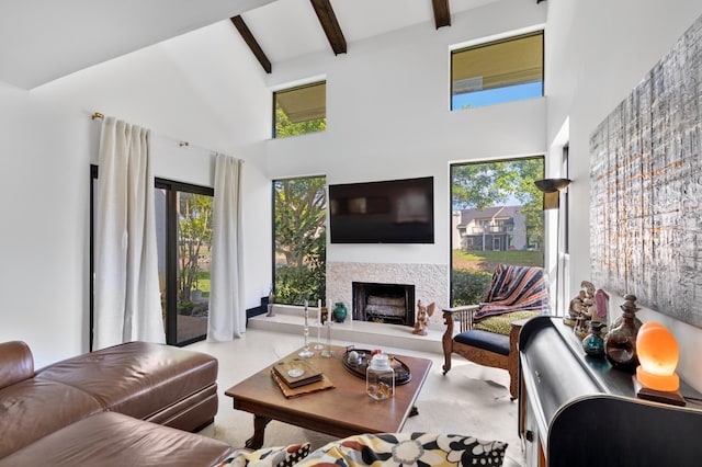 living room featuring a fireplace with raised hearth, a high ceiling, and beamed ceiling