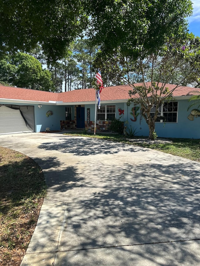 ranch-style home with a garage, driveway, and stucco siding