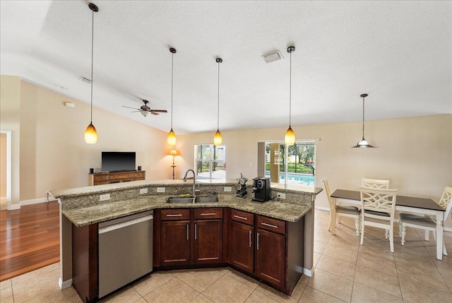 kitchen with a sink, vaulted ceiling, open floor plan, stainless steel dishwasher, and decorative light fixtures