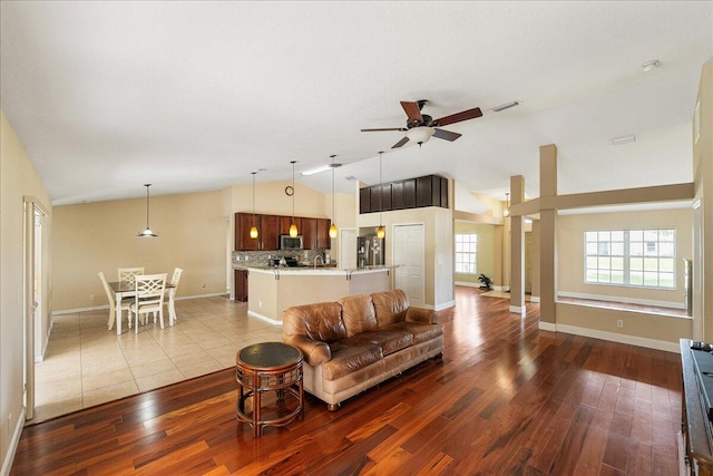 living room with ceiling fan, vaulted ceiling, baseboards, and wood finished floors