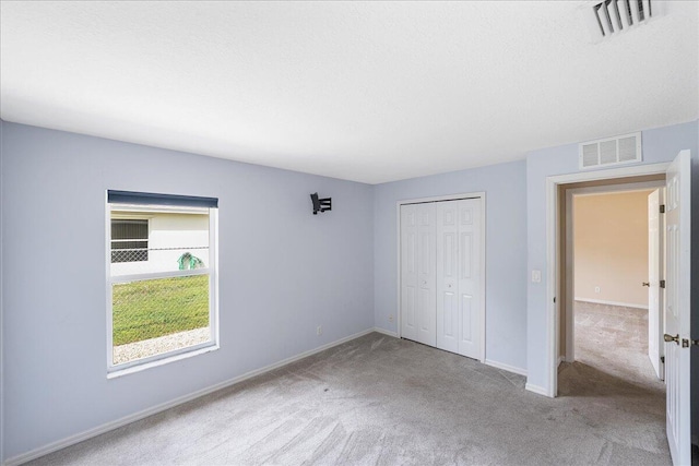 unfurnished bedroom with baseboards, visible vents, a closet, and carpet flooring