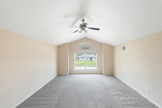 empty room with ceiling fan, a textured ceiling, baseboards, vaulted ceiling, and carpet