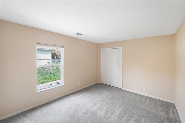 unfurnished bedroom featuring a closet, carpet flooring, visible vents, and baseboards