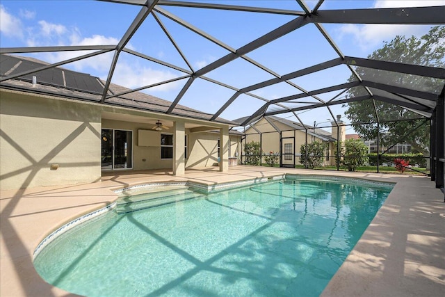 pool featuring glass enclosure, a patio area, and a ceiling fan