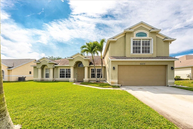 view of front facade with central AC unit, an attached garage, driveway, stucco siding, and a front yard