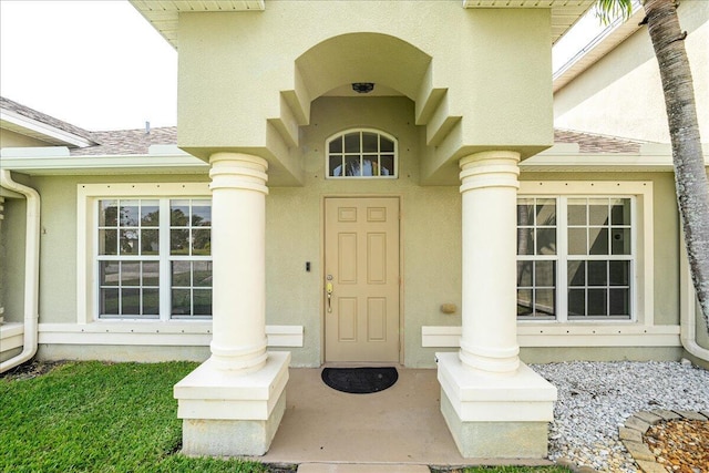 doorway to property with roof with shingles and stucco siding