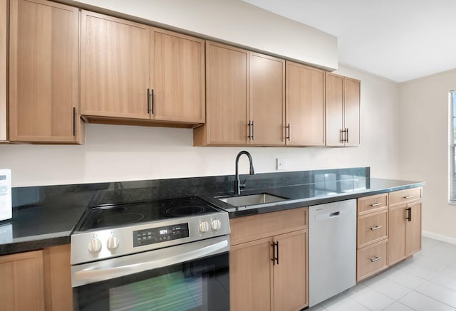 kitchen with light brown cabinets, baseboards, dark stone counters, appliances with stainless steel finishes, and a sink