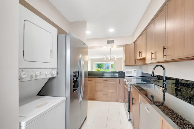 kitchen featuring white microwave, visible vents, stainless steel fridge with ice dispenser, light brown cabinetry, and stacked washer and dryer