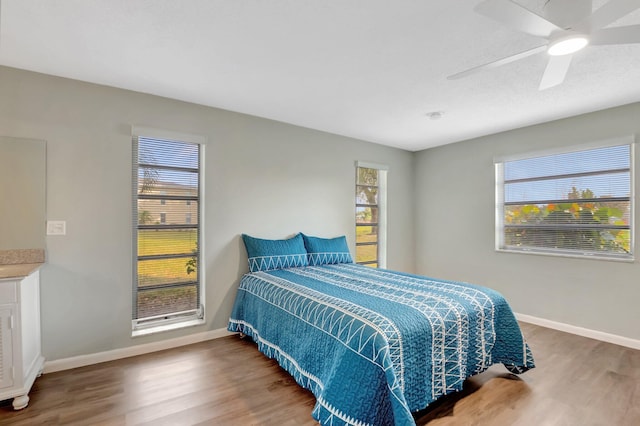 bedroom with ceiling fan, multiple windows, and wood finished floors