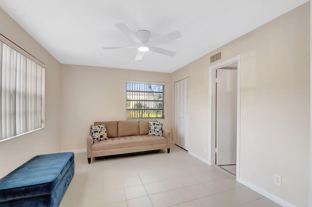 living area featuring light tile patterned floors, baseboards, visible vents, and ceiling fan