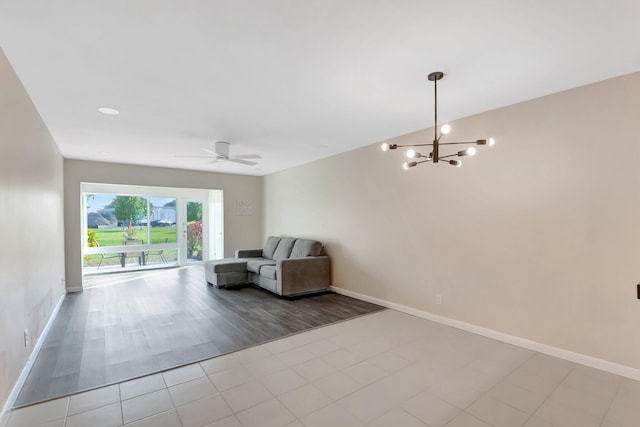 unfurnished room with baseboards, ceiling fan with notable chandelier, and tile patterned flooring