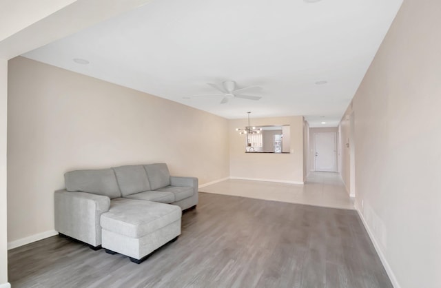 unfurnished room featuring light wood-type flooring, baseboards, and ceiling fan with notable chandelier