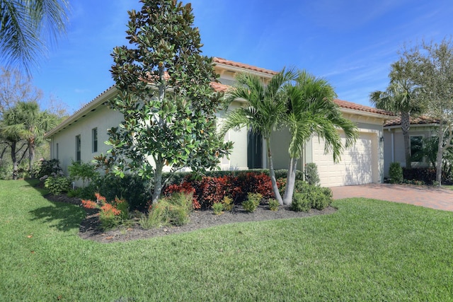 view of front of home with a garage, a tile roof, decorative driveway, and a front yard