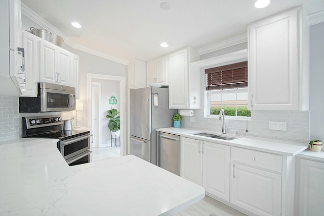 kitchen with crown molding, appliances with stainless steel finishes, white cabinets, and a sink