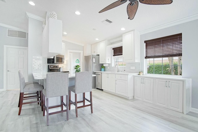 kitchen with white cabinets, visible vents, a sink, and a breakfast bar area