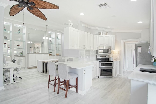 kitchen featuring visible vents, white cabinets, appliances with stainless steel finishes, a peninsula, and backsplash