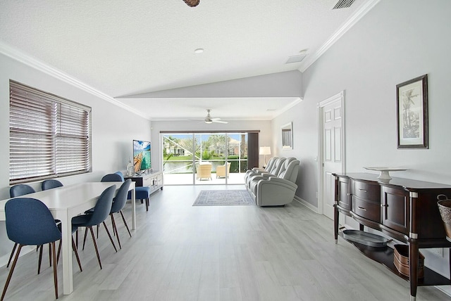 living area with vaulted ceiling, crown molding, light wood finished floors, and ceiling fan