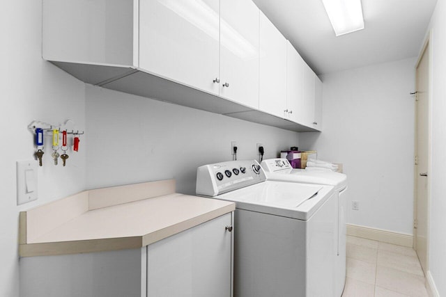 clothes washing area featuring cabinet space, light tile patterned floors, baseboards, and washer and clothes dryer