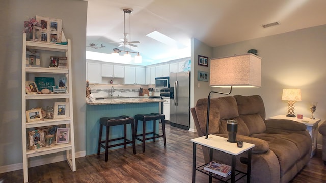 kitchen featuring dark wood-style floors, stainless steel appliances, visible vents, white cabinets, and a peninsula