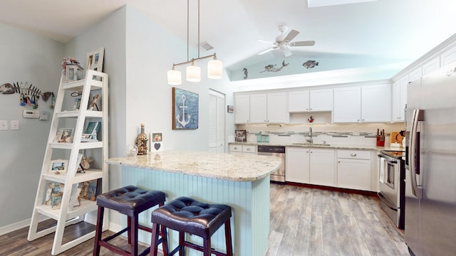 kitchen featuring light stone countertops, appliances with stainless steel finishes, white cabinets, and a sink