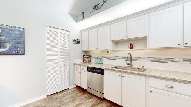 kitchen featuring tasteful backsplash, a sink, light wood-style flooring, and stainless steel dishwasher