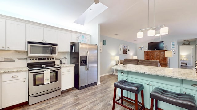 kitchen with light wood-style flooring, a breakfast bar area, appliances with stainless steel finishes, open floor plan, and backsplash