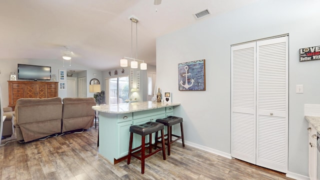 kitchen with a breakfast bar, ceiling fan, a peninsula, and wood finished floors