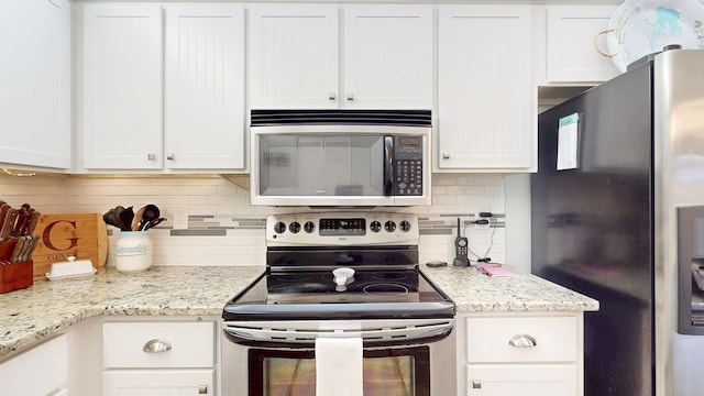 kitchen featuring stainless steel appliances, light stone counters, white cabinetry, and decorative backsplash