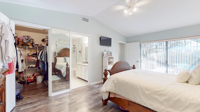 bedroom with wood finished floors, visible vents, vaulted ceiling, a closet, and a walk in closet