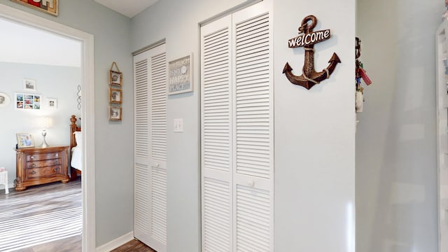 corridor with baseboards and wood finished floors