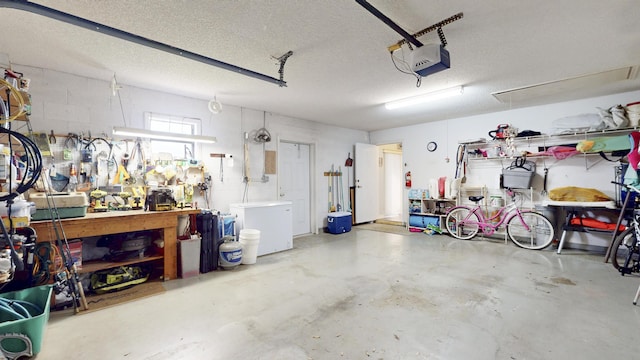 garage with a garage door opener, refrigerator, and a workshop area